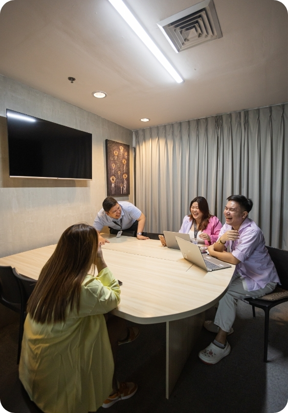 Makati City Virtual Office The Company Makati (2) A small team of four gathers around a sleek conference table, laughing during a brainstorming session inside The Company Makati. The professional meeting room is part of the flexible offerings with a Virtual Office in Makati.
