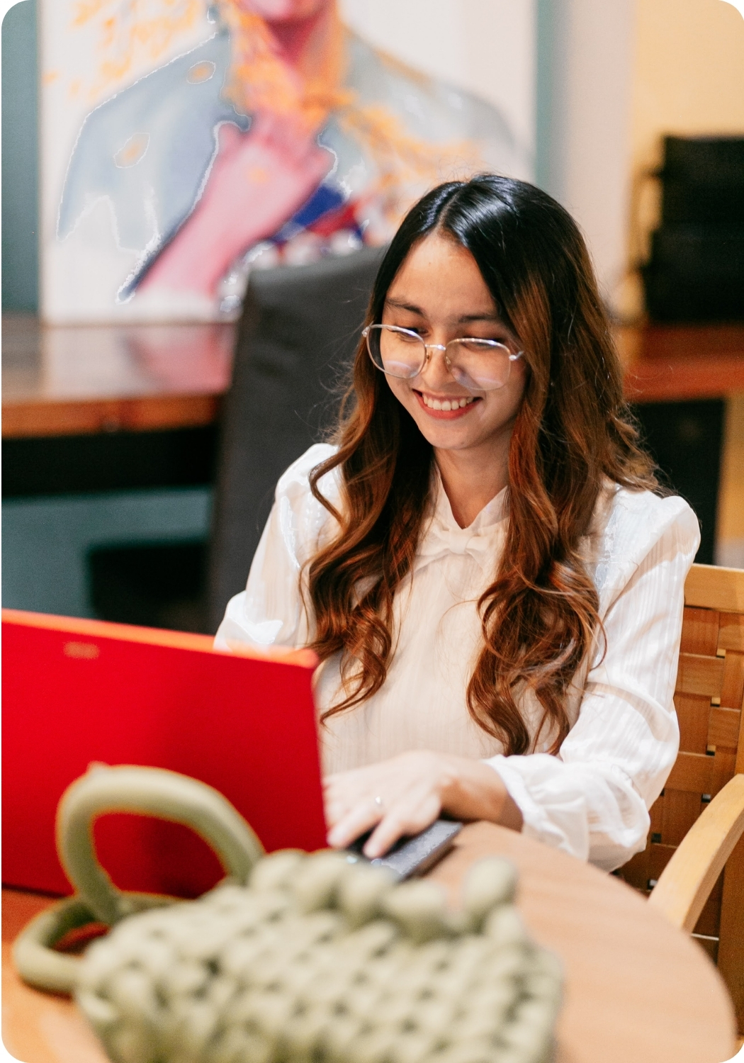 Woman with glasses typing on a red laptop in a cozy coworking lounge, showcasing a modern office for rent in Cebu.